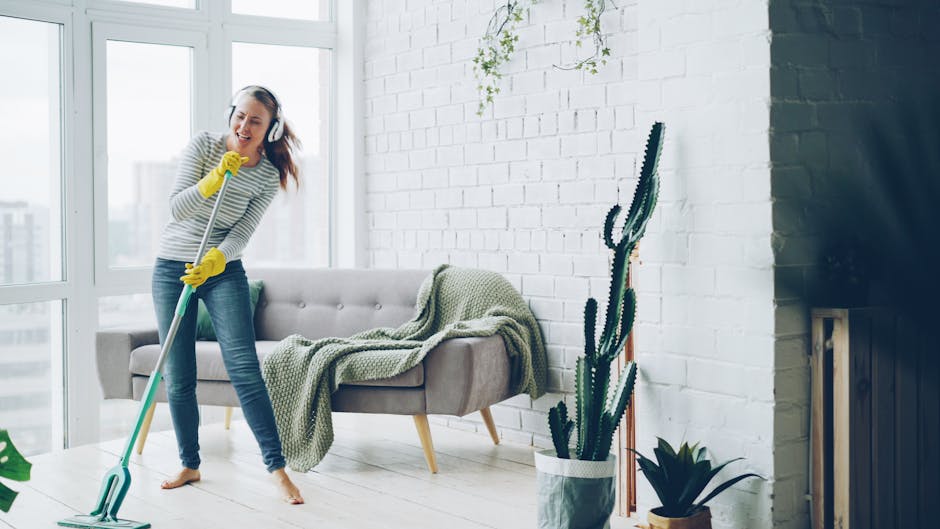 Happy woman listening to music while mopping a modern living room.